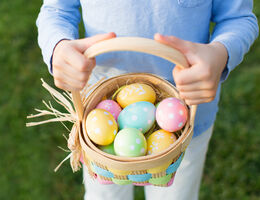 Photo of a child's hands holding an Easter egg basket.